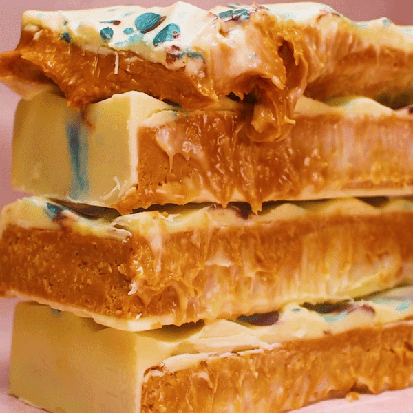 A close-up stack of a Biscoff Kunafa White Chocolate Bar XL by Urban Chocolatier, featuring a creamy white chocolate exterior and crispy kunafa filling. 
